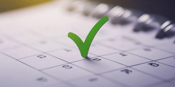 A calendar page with a green check mark on one of the dates, symbolizing completion or a scheduled event. key dates